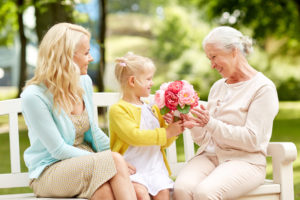 happy family giving flowers to grandmother at park