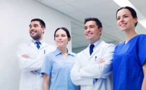 clinic, profession, people, health care and medicine concept - group of happy medics or doctors at hospital corridor