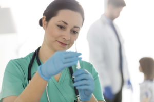 Confident smiling nurse checking syringe at hospital