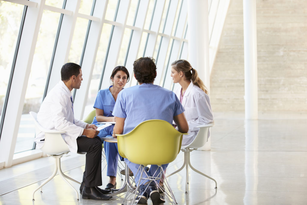 Medical Team Meeting Around Table In Modern Hospital
